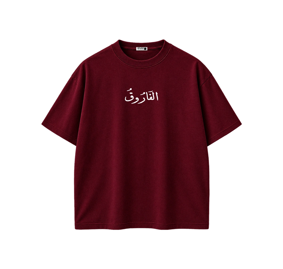 A short-sleeve crewneck t-shirt in deep burgundy with white Arabic calligraphy printed on the center chest, displayed flat against a solid white background.
