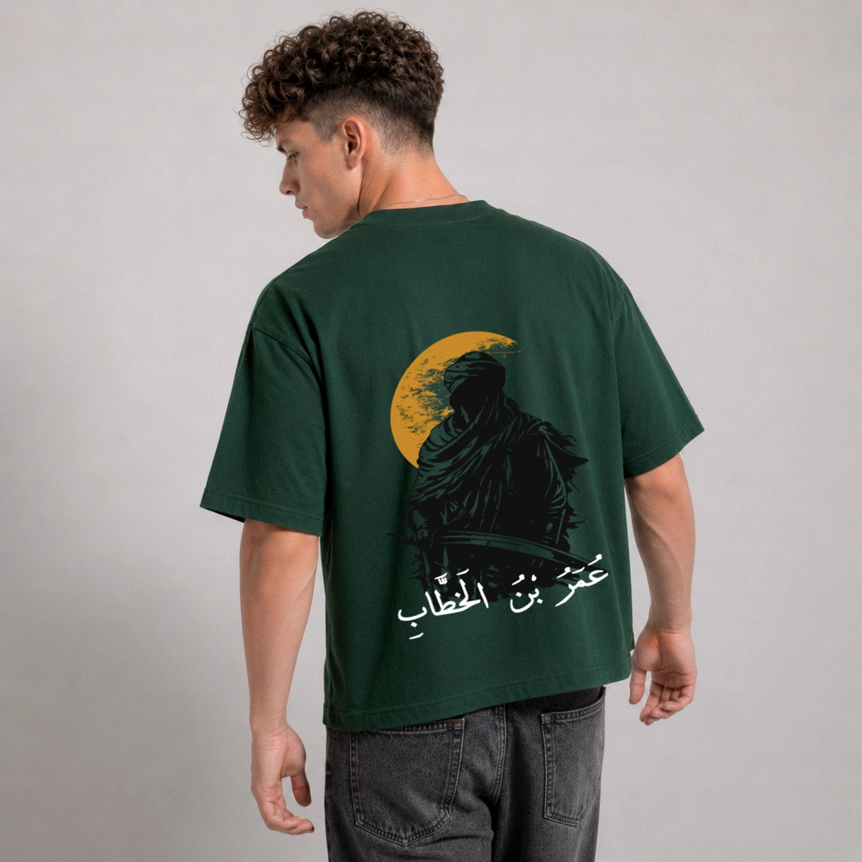 Man wearing a green t-shirt with a graphic design on the back against a gray background