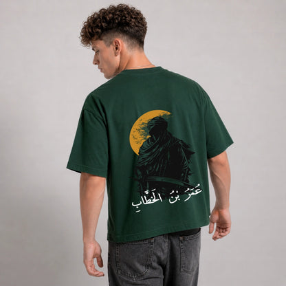 Man wearing a green t-shirt with a graphic design on the back against a gray background