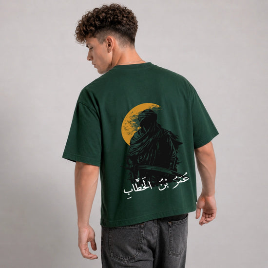 Man wearing a green t-shirt with a graphic design on the back against a gray background