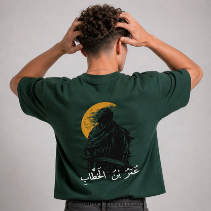 Person wearing a green t-shirt with a graphic design on the back against a gray background
