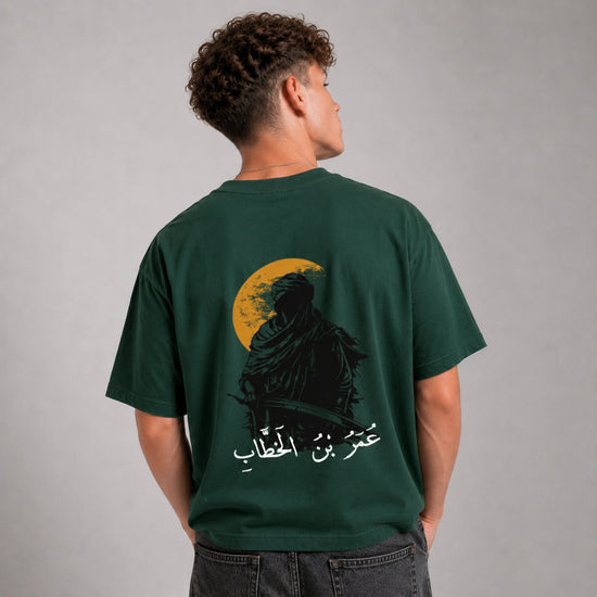Person wearing a green t-shirt with a graphic design on the back against a gray background