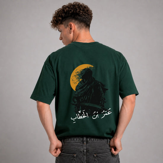 Person wearing a green t-shirt with a graphic design on the back against a gray background