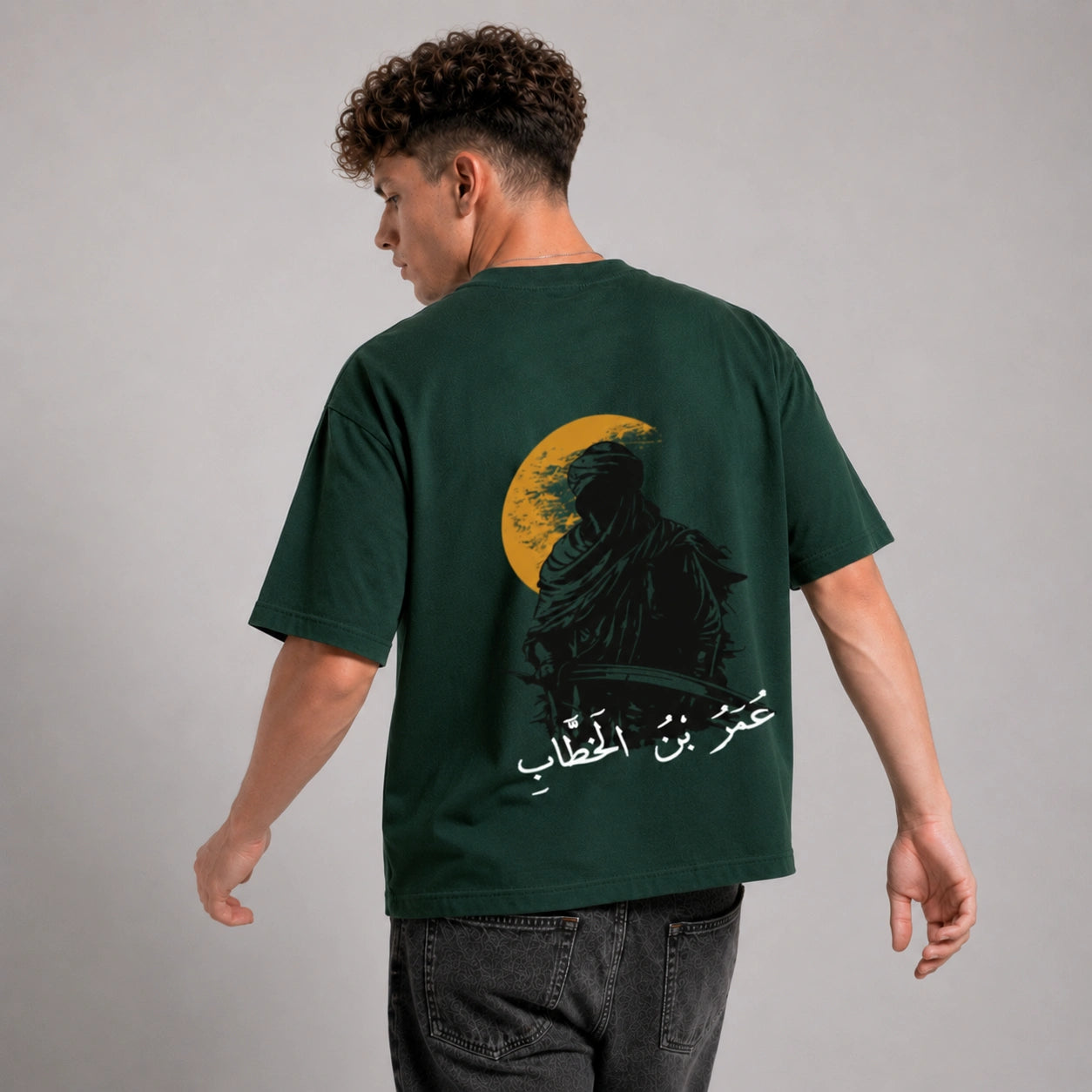 Person wearing a green t-shirt with a graphic design on the back against a gray background