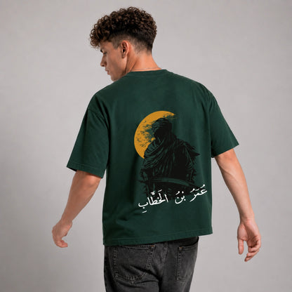 Person wearing a green t-shirt with a graphic design on the back against a gray background