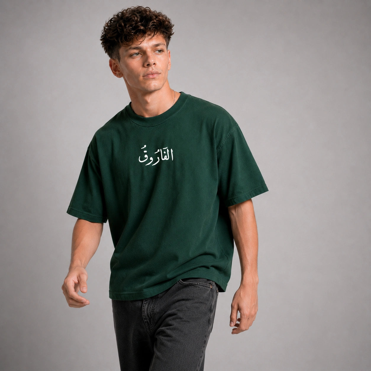 Person wearing a green t-shirt with Arabic text on a gray background