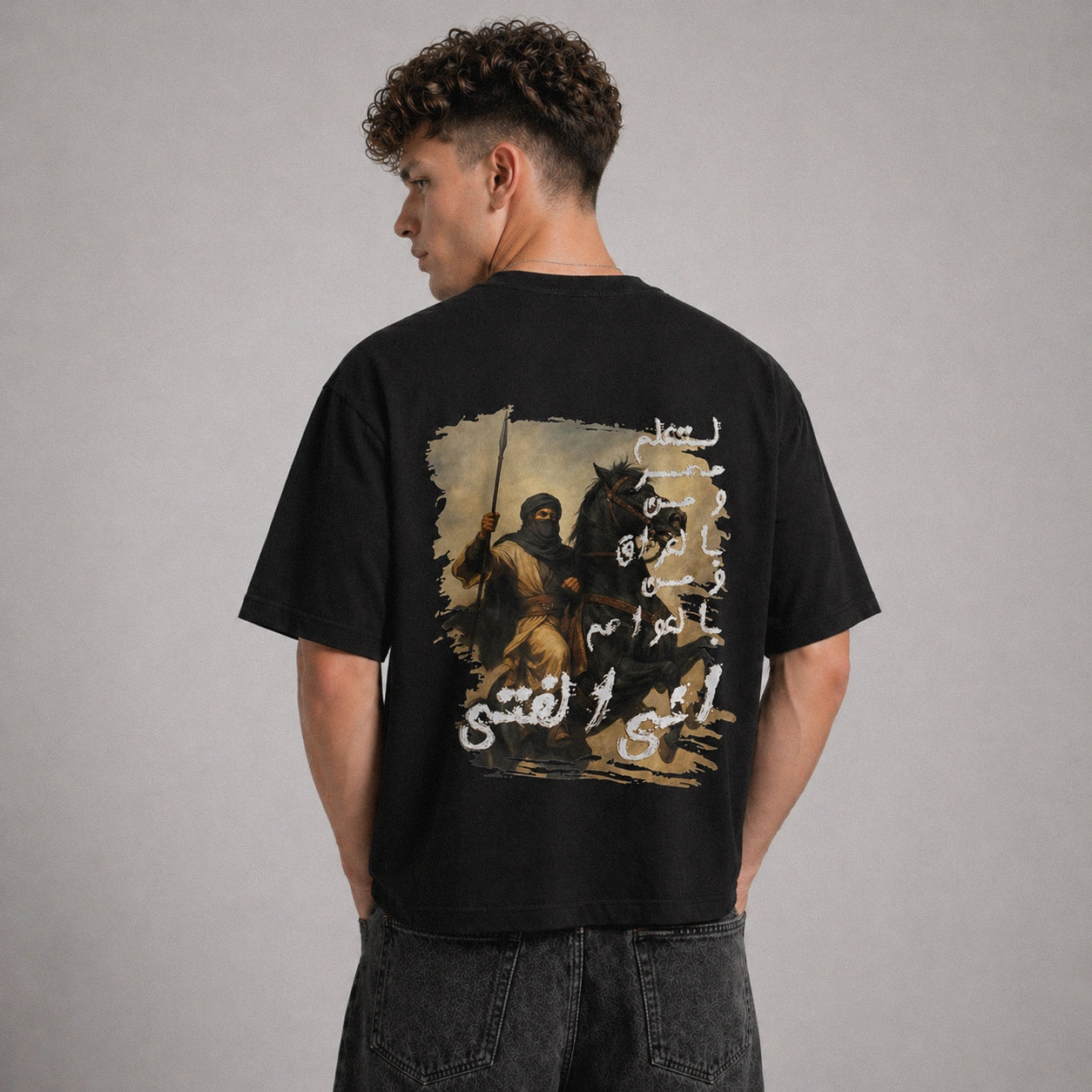 Person wearing a black t-shirt with a graphic design on the back against a gray background