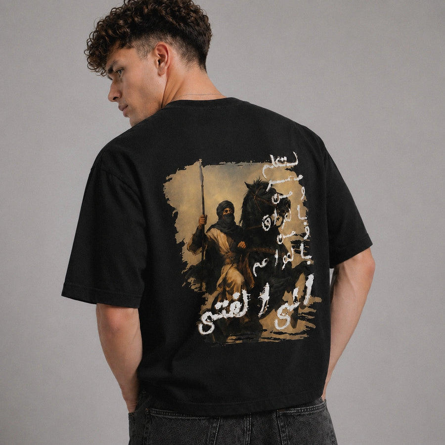 Person wearing a black t-shirt with a graphic design on the back against a gray background