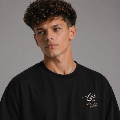 Man wearing a black sweatshirt with Arabic text on a gray background