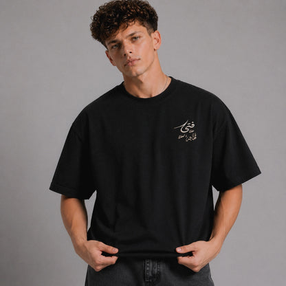 Person wearing a black t-shirt with Arabic text on a gray background
