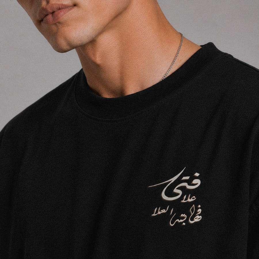 Black t-shirt with white Arabic text on a gray background