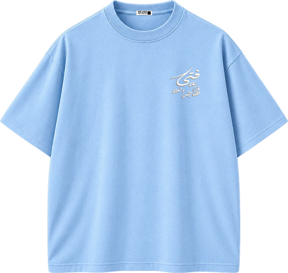 A light blue short-sleeve crewneck t-shirt with a small white Arabic calligraphy graphic on the left chest, displayed on a clean white background.