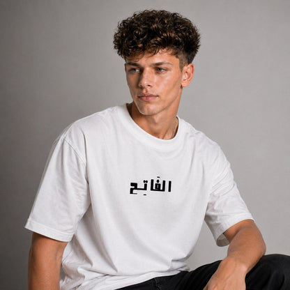 Person wearing a white t-shirt with Arabic text on a gray background