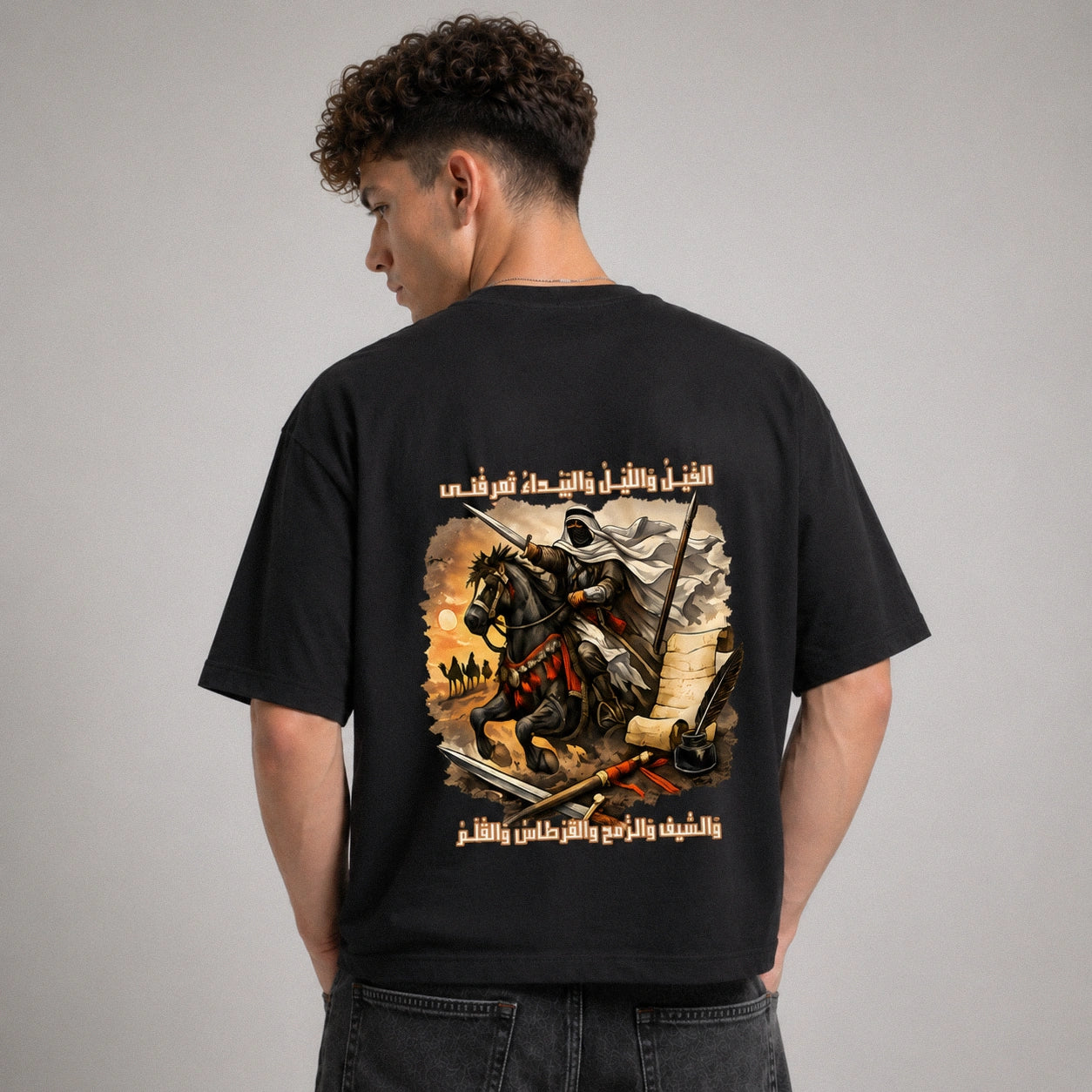 Person wearing a black t-shirt with a graphic design on the back against a gray background