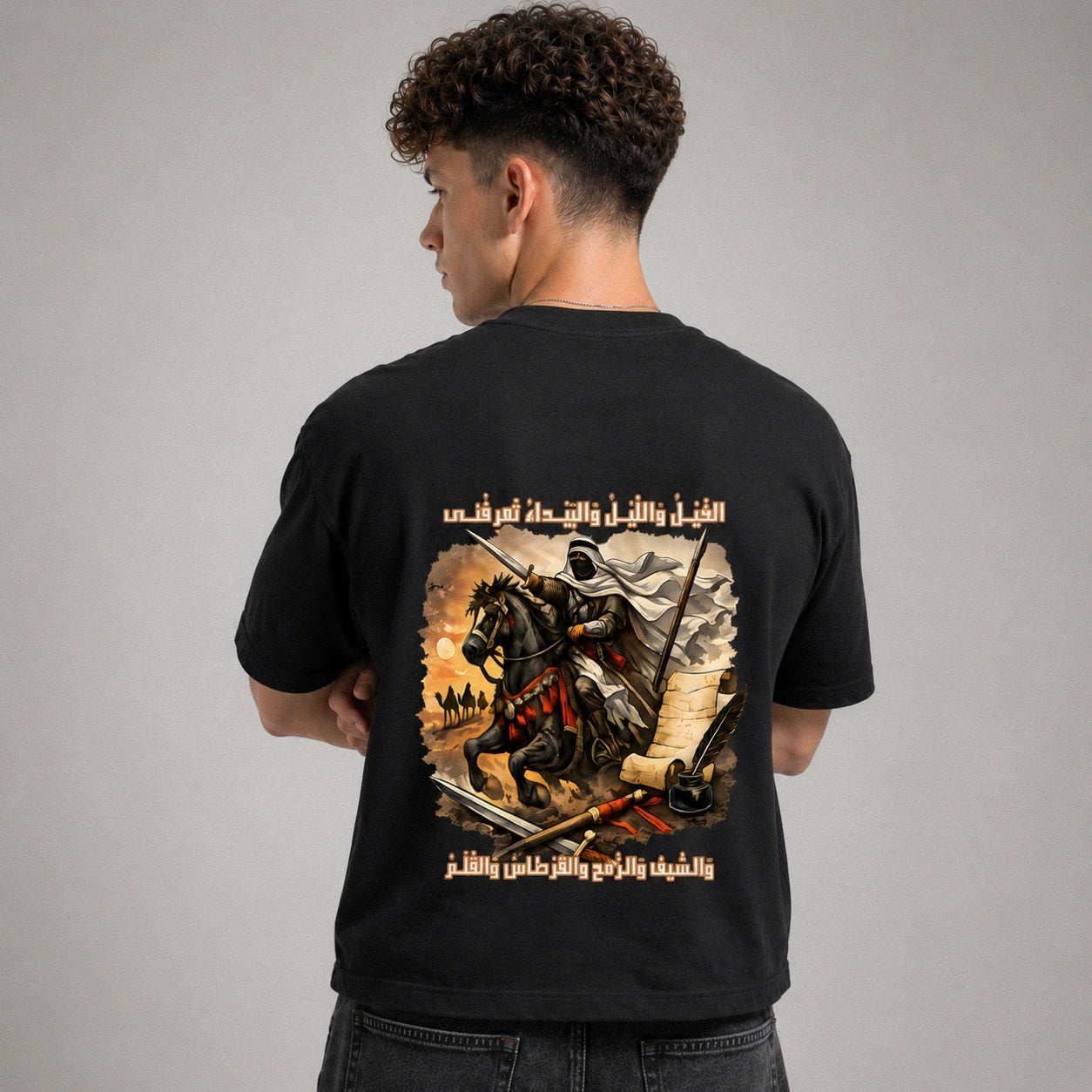 Person wearing a black t-shirt with a graphic design on the back against a gray background