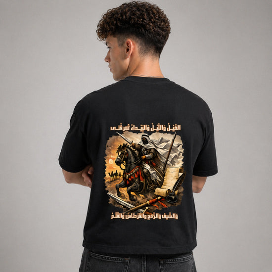 Person wearing a black t-shirt with a graphic design on the back against a gray background