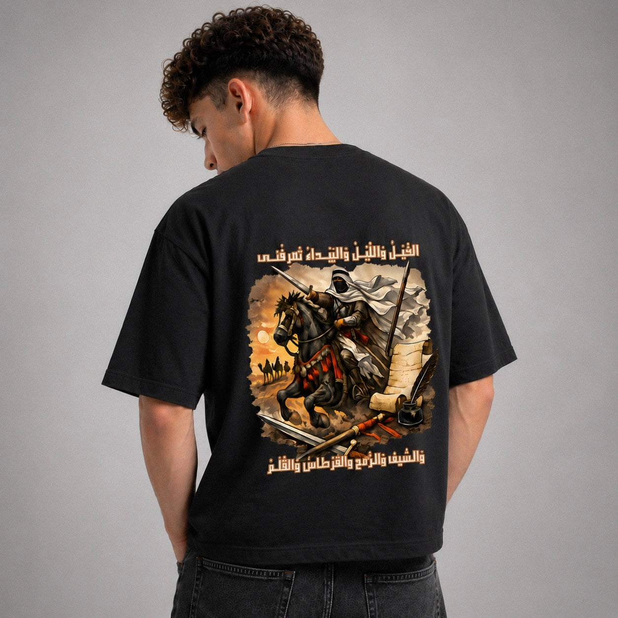Person wearing a black t-shirt with a graphic design on the back against a gray background