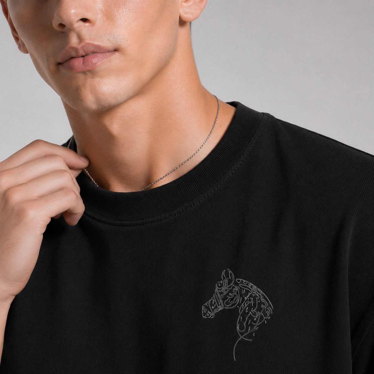 Person wearing a black sweatshirt with a horse design on a gray background