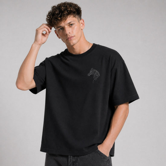 Man wearing a black t-shirt with a small logo on a gray background