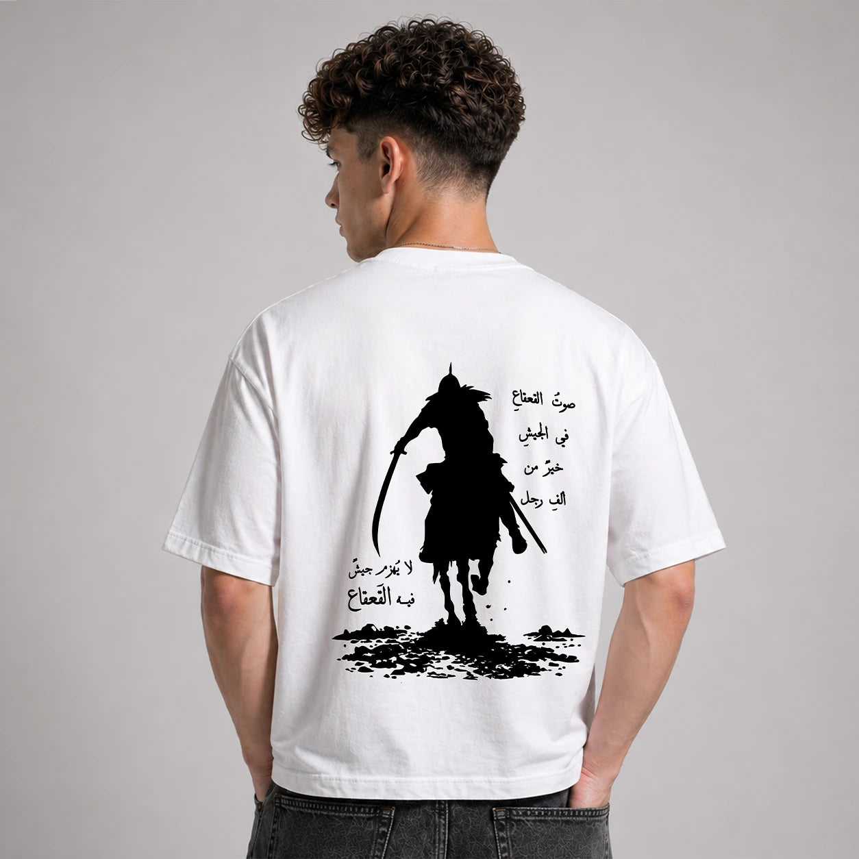 Person wearing a white t-shirt with a black silhouette design on the back against a gray background