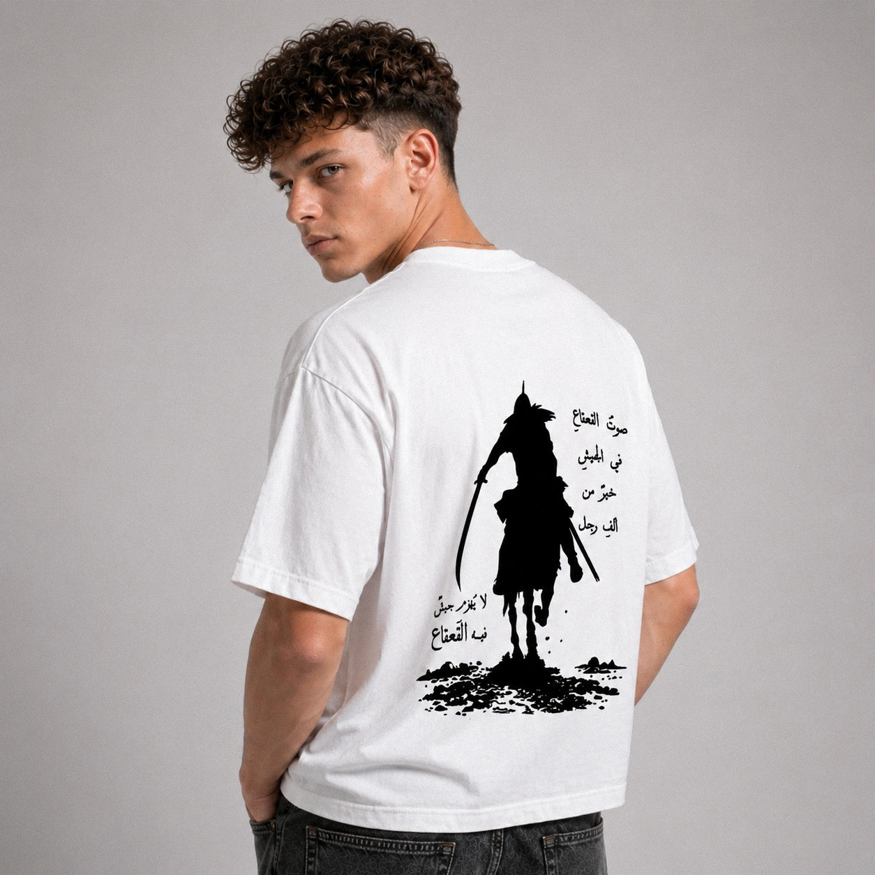 Man wearing a white t-shirt with a black graphic design on the back against a gray background