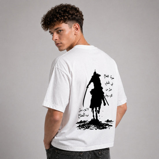 Man wearing a white t-shirt with a black graphic design on the back against a gray background