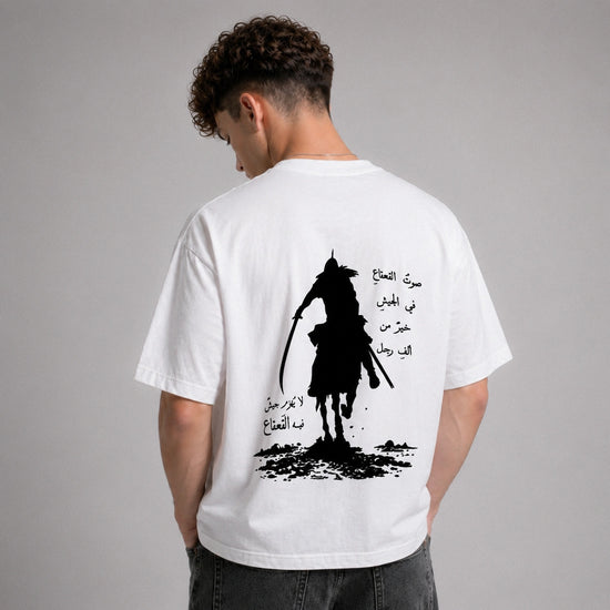 Person wearing a white t-shirt with a black silhouette design and Arabic text on the back, against a gray background.