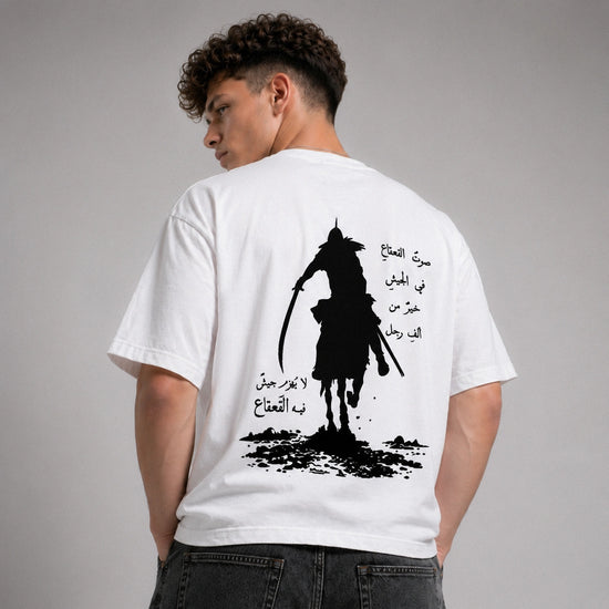 Person wearing a white t-shirt with a black silhouette design and Arabic text on the back.