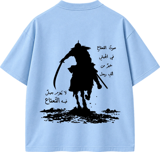 A light blue short-sleeve T-shirt shown from the back, featuring a large black graphic of a silhouetted rider on horseback with Arabic text printed around it.
