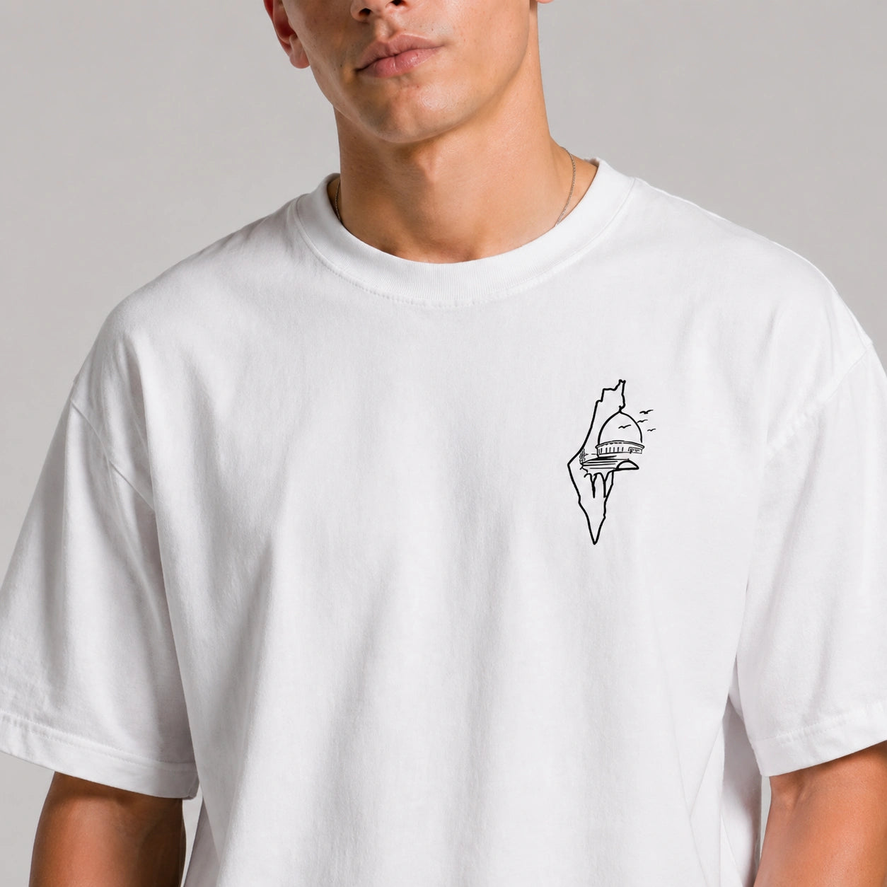 Person wearing a white t-shirt with a black graphic design on a plain background