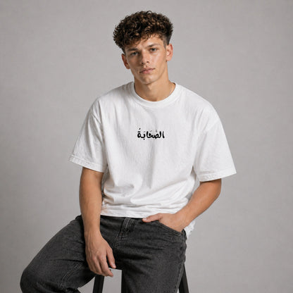 Person wearing a white t-shirt with Arabic text on a gray background