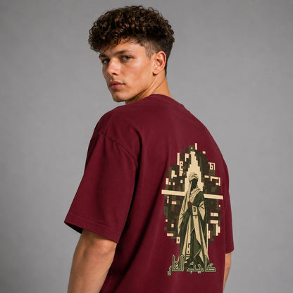 A man wearing a maroon t-shirt, shown from the back to highlight a large graphic print featuring a pixelated figure and Arabic calligraphy on a gray studio background.
