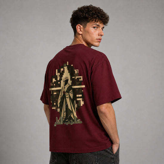 A man wearing a maroon t-shirt with a large graphic print on the back, photographed from behind against a neutral gray studio background.