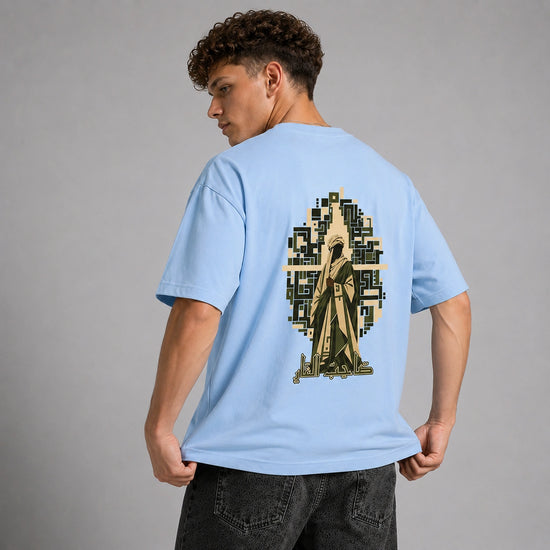 A man wearing a light blue t-shirt with a large graphic print on the back, shown from behind against a neutral gray studio background.