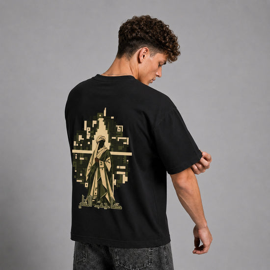 A man wearing a black t-shirt with a large pixelated graphic on the back, shown from behind against a gray studio background.