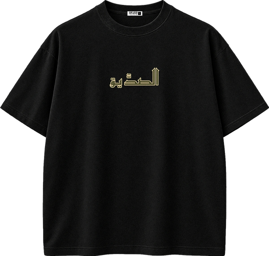 A black short-sleeve crewneck t-shirt with gold Arabic calligraphy printed across the chest, displayed on a clean white background.