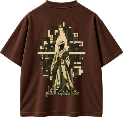 A brown short-sleeve t-shirt shown from the back, featuring a large graphic print of a robed figure in beige and olive green, set against a pixelated background with Arabic calligraphy below.