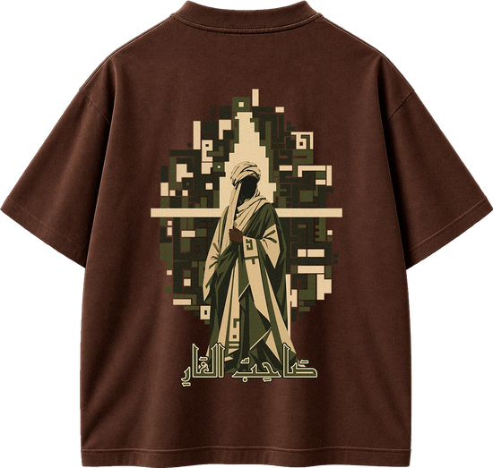 A brown short-sleeve t-shirt shown from the back, featuring a large graphic print of a robed figure in beige and olive green, set against a pixelated background with Arabic calligraphy below.