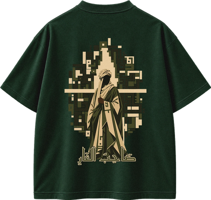 A dark forest green short-sleeve t-shirt shown from the back, featuring a large graphic print of a pixelated figure in beige and olive green robes with Arabic calligraphy below.