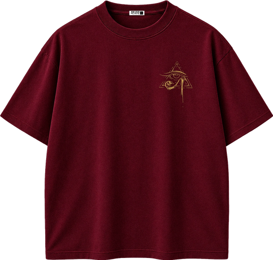 A dark burgundy short-sleeve t-shirt with a small gold Egyptian eye and pyramid graphic on the left chest, displayed on a clean white background.