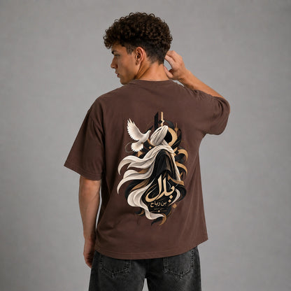 A man wearing a brown t-shirt with a large graphic print on the back, shown from behind against a gray studio background.