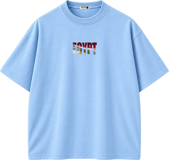 A light blue short-sleeve crewneck t-shirt with a graphic print on the chest spelling 'EGYPT' in a stylized font containing red, white, and blue elements. The shirt is displayed flat against a solid white background.