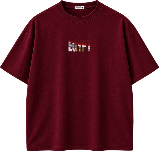A dark red short-sleeve crewneck t-shirt with a small chest graphic featuring the word 'REVIVAL' in a distressed, layered red, white, and gold design. The shirt is displayed flat against a solid white background.