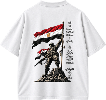 White short-sleeve t-shirt showing the back graphic print. The design features a soldier standing on rocks holding the Egyptian flag, with Arabic calligraphy printed vertically alongside.