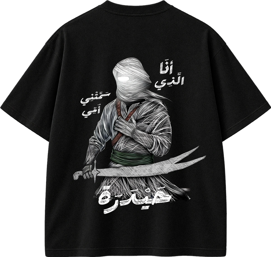 A black short-sleeve t-shirt shown from the back, featuring a large graphic print of a hooded figure wrapped in bandages holding a sword, with Arabic text printed around the design.