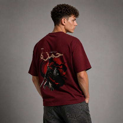 A man wearing a maroon t-shirt with a large graphic print on the back, shown from behind against a gray studio background.