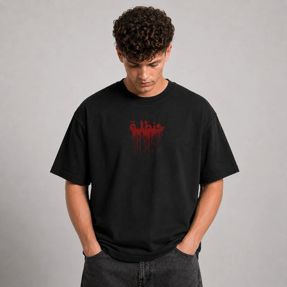 A man wearing a black crewneck t-shirt with a red dripping graphic on the chest, paired with dark gray jeans, standing against a neutral gray background.