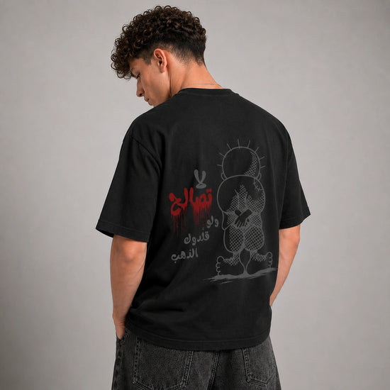 A man wearing a black graphic t-shirt, viewed from behind. The back of the shirt features a detailed gray cartoon rabbit design with Arabic text in red and gray.