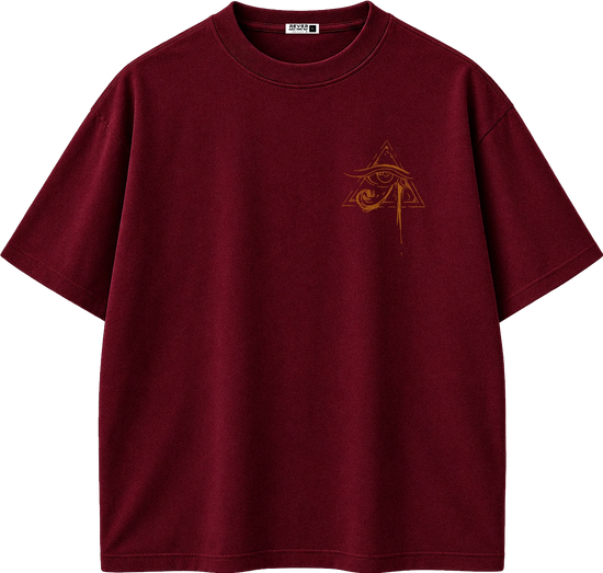 A dark burgundy short-sleeve t-shirt with a small gold Egyptian eye and pyramid graphic on the left chest, displayed on a clean white background.