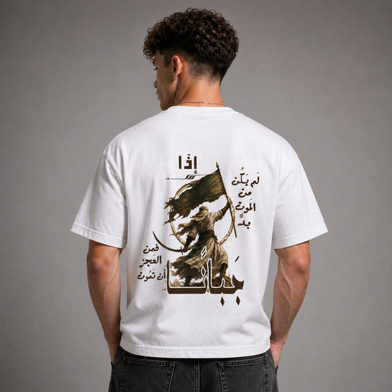 A man shown from the back wearing a white t-shirt with a large graphic print featuring Arabic calligraphy and a warrior illustration in black and brown, set against a plain gray studio background.